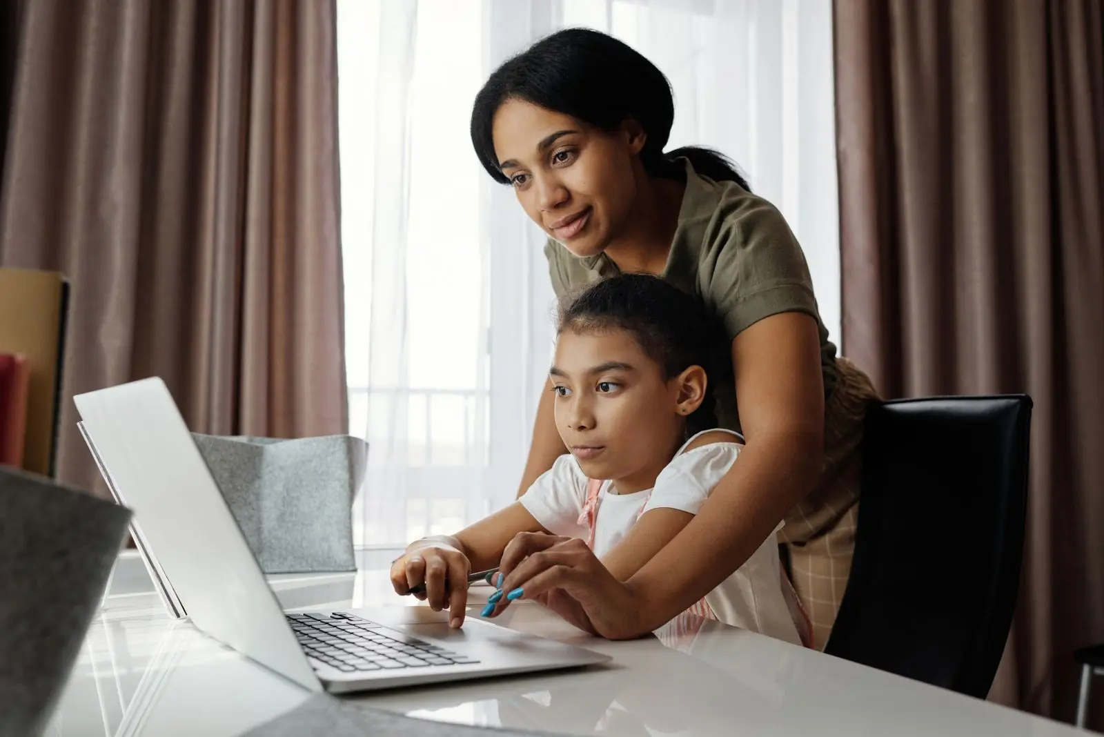 Parent helping a child learn on a laptop at home &mdash; edtech and online-course learning