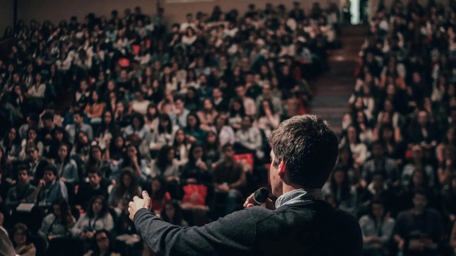 A confident speaker addressing a large audience — illustrating B2B and commercial AI avatar video use cases such as pitch videos, product explainers, and brand spokesperson spots.