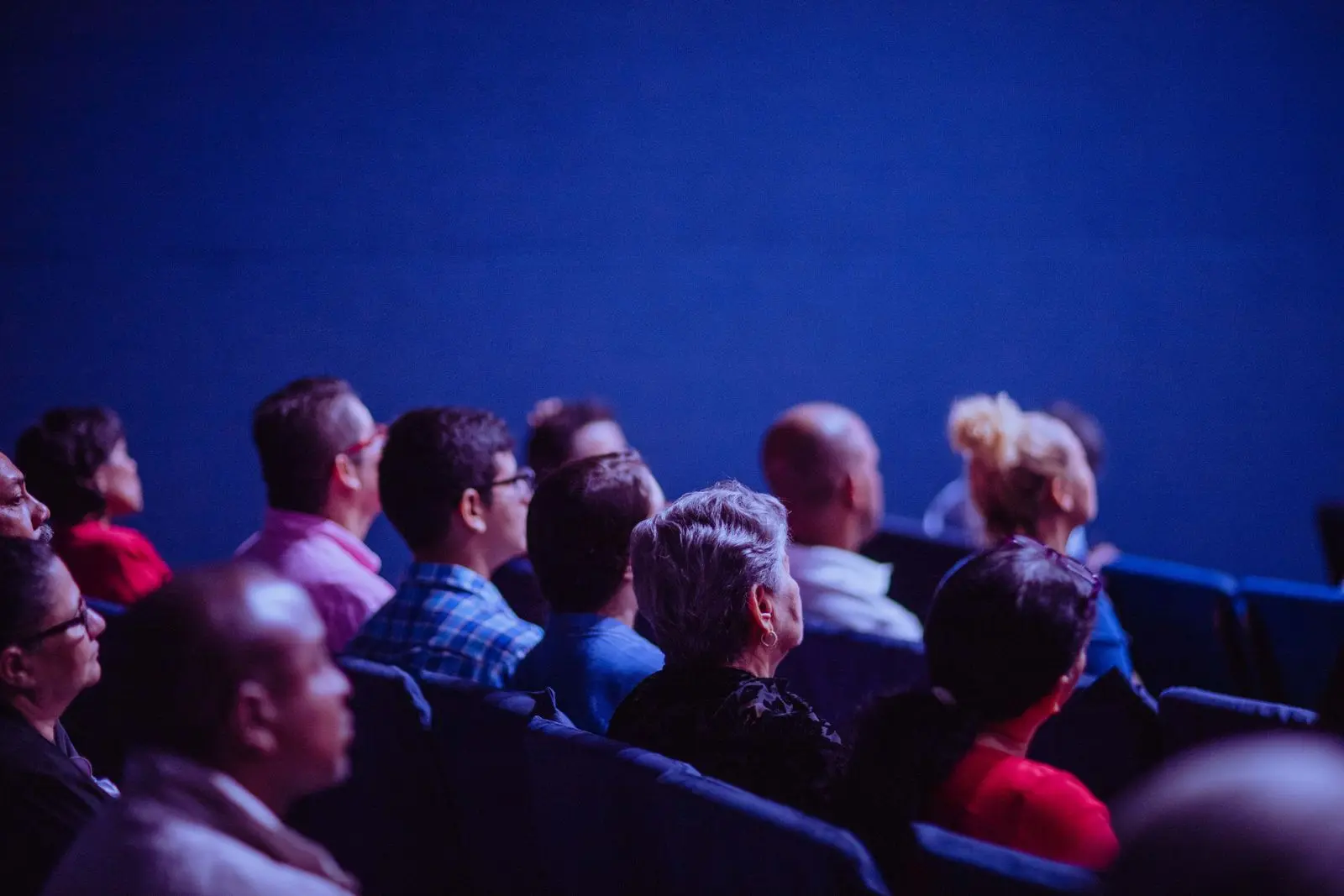 Event audience seated in a darkened auditorium watching the screen during a post-event recap