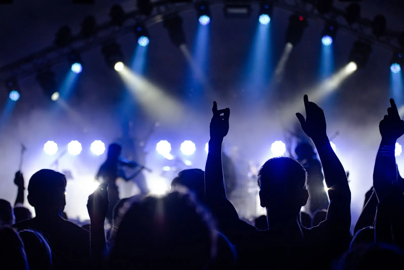 Live event crowd with raised hands lit by blue stage lights during a sizzle-reel moment